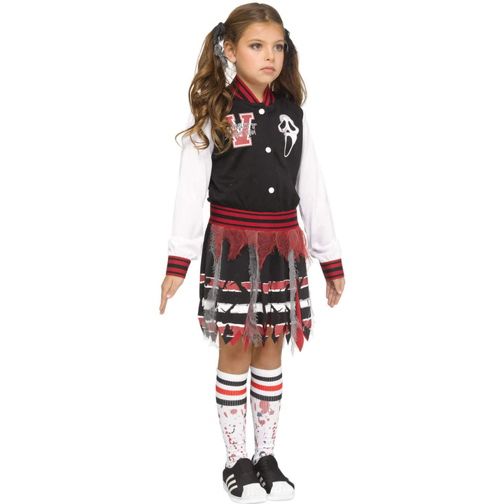 A young girl modeling a Scream varsity girl Halloween costume against a plain white background. The costume includes a black and red varsity jacket with a V and Ghost face graphic, a white long-sleeve shirt, a black and red frayed skirt, and matching blood-splattered knee socks.