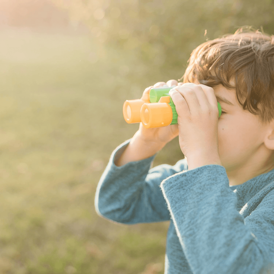 little boy uses binoculars to look into the distance