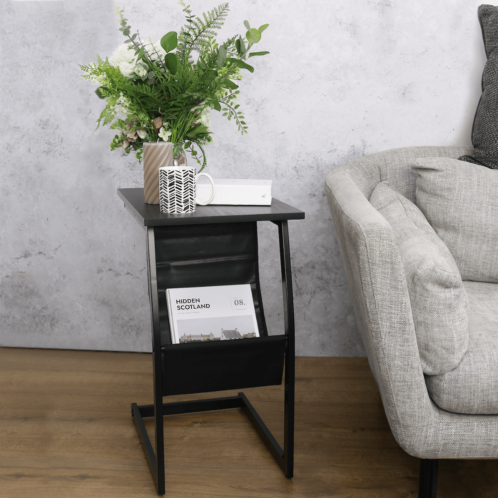 magazine rack side table styled beside sofa with coffee mug, candle and magazines