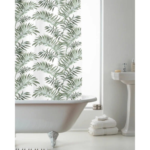 Green jungle leaf pattern shower curtain hanging over a bath, with white towels and sink