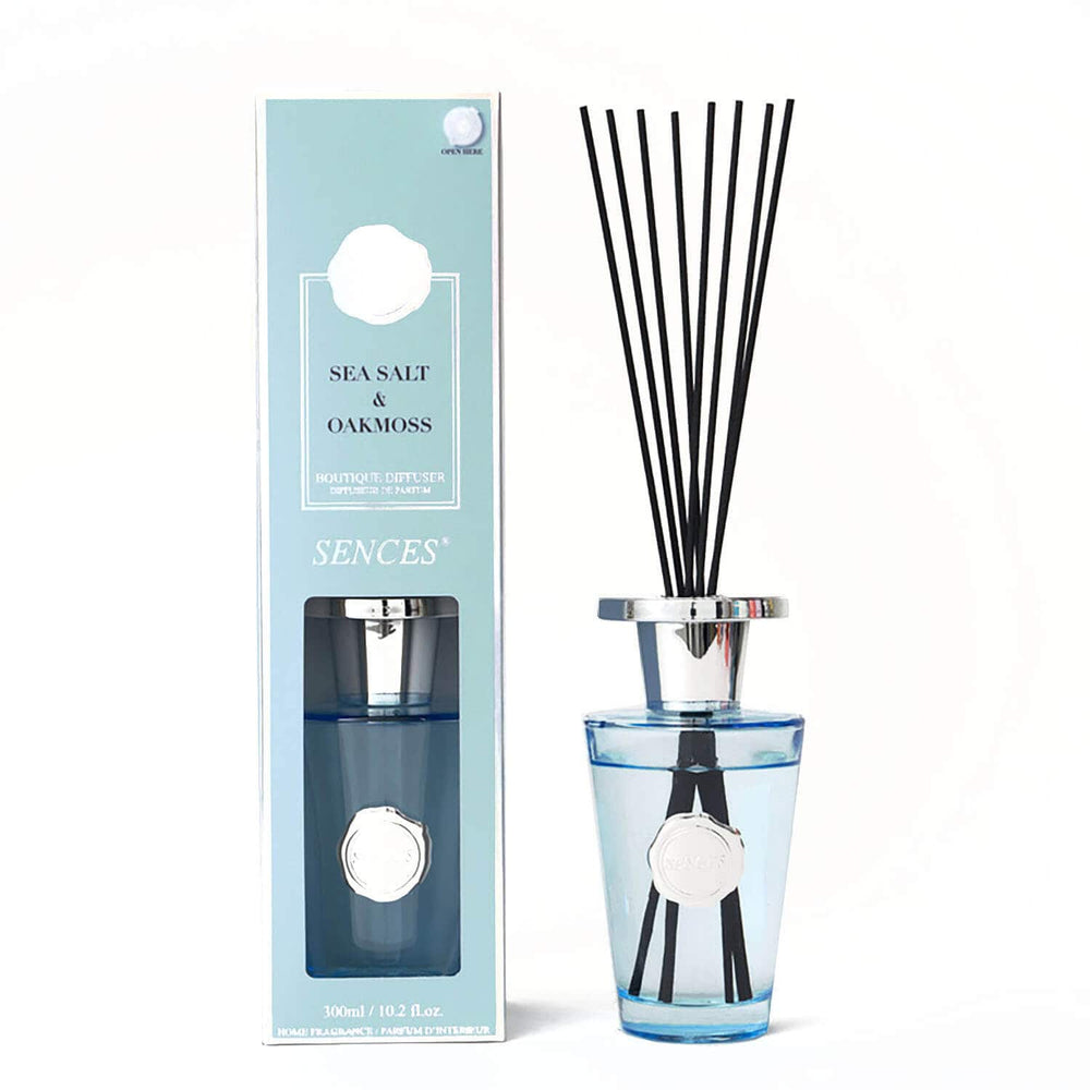 Sea sat and oakmoss scented reed diffuser bottle with black reeds and a light blue glass base stands next to its matching light blue box.