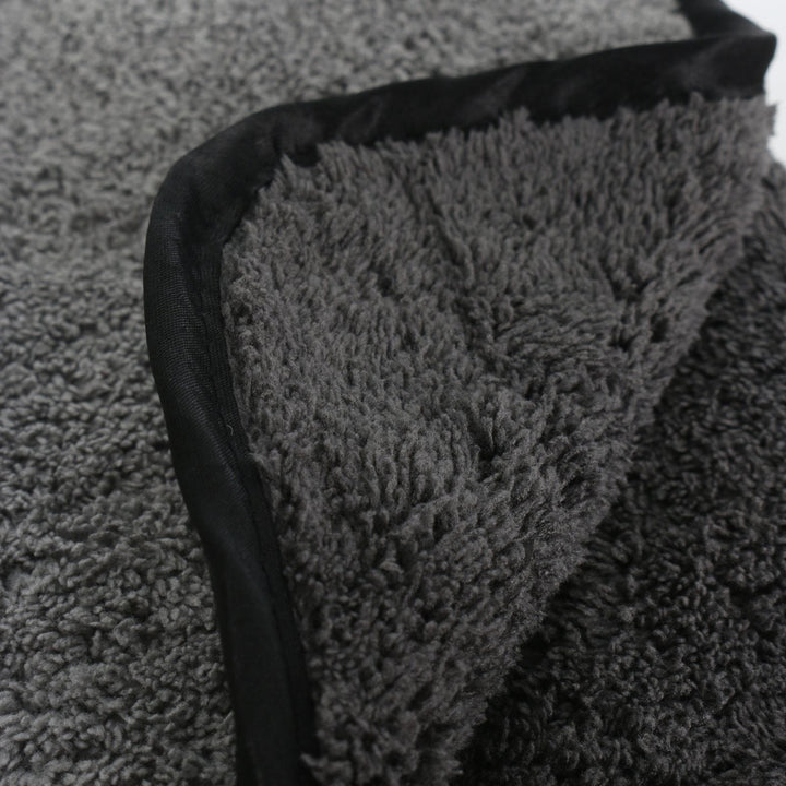 Close-up of a textured grey microfibre towel with a black border on a white background
