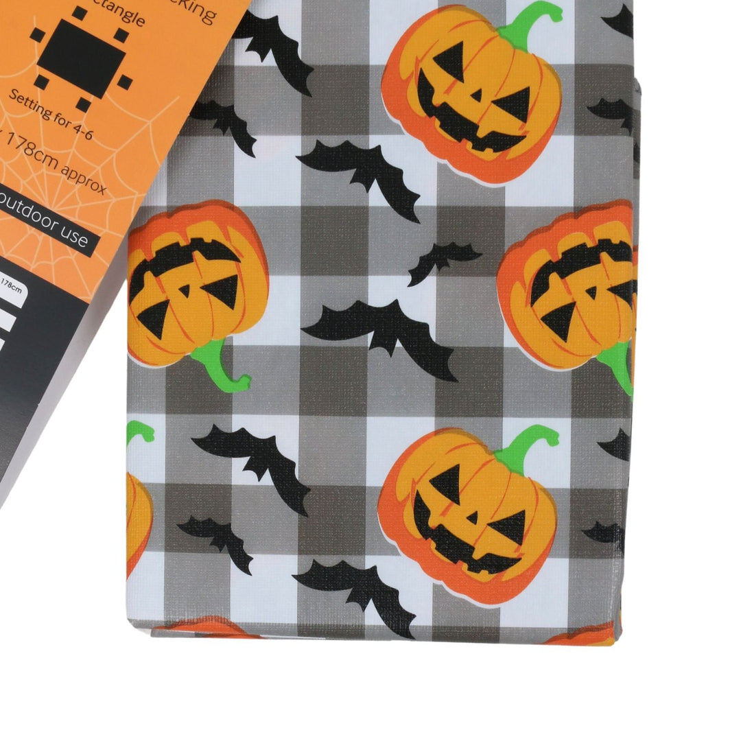 Halloween-themed fabric with a gray and white buffalo plaid pattern, decorated with orange jack-o'-lantern pumpkins and black bats. An orange packaging tag is partially visible on the top left.