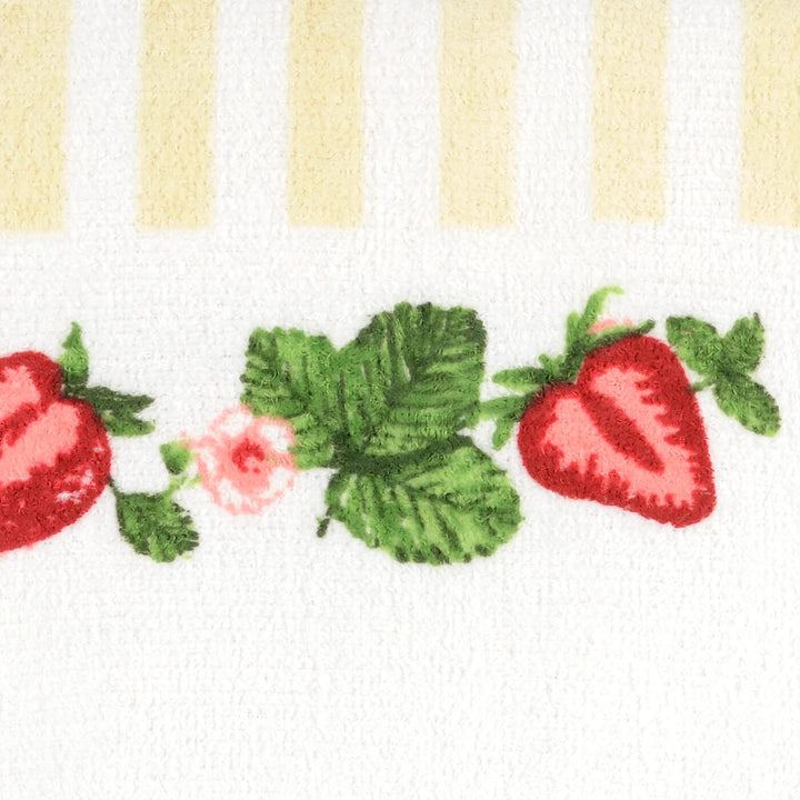 Strawberries and leaves on a white tea towel with beige stripes