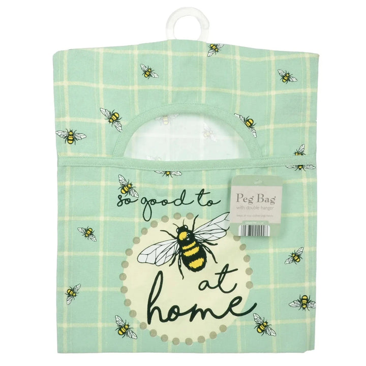 Peg bag with bee design and text 'So good to be at home' on a green checkered background.