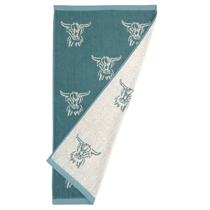 Hand towel with reversible teal and white highland cow head pattern