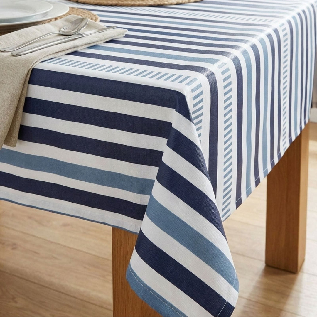 Nautical striped tablecloth on a wooden table with silverware and napkins.