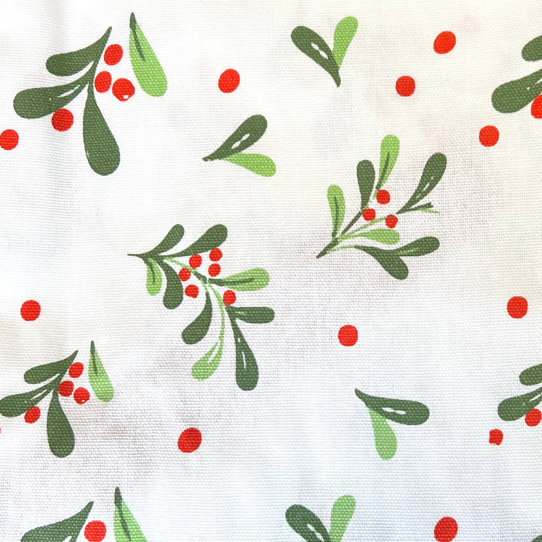 White fabric with a repeating pattern of green mistletoe branches and red berries.