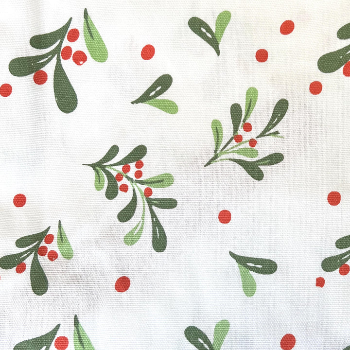 Cose up of mistletoe leaves and red berries on white fabric