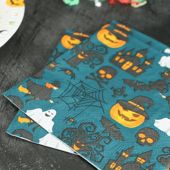 haunted house &amp; grinning pumpkin napkins on a halloween table with party streamers in the background