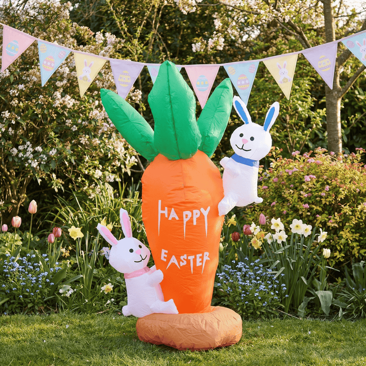 Inflatable carrot with 'Happy Easter' text and two bunny figures in a garden setting with bunting.