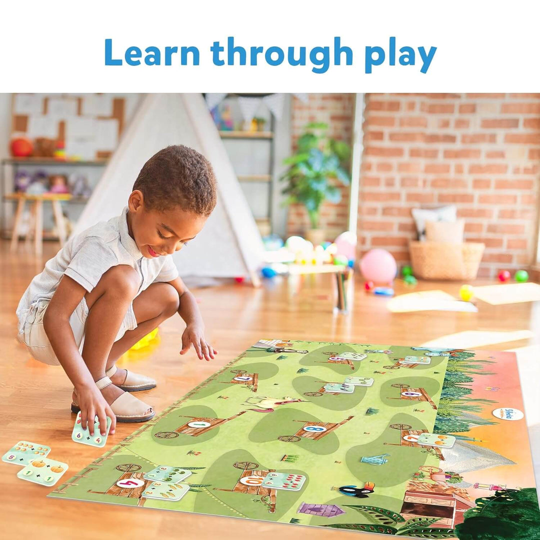 Child playing with a colorful mat and cards on a wooden floor in a playroom.