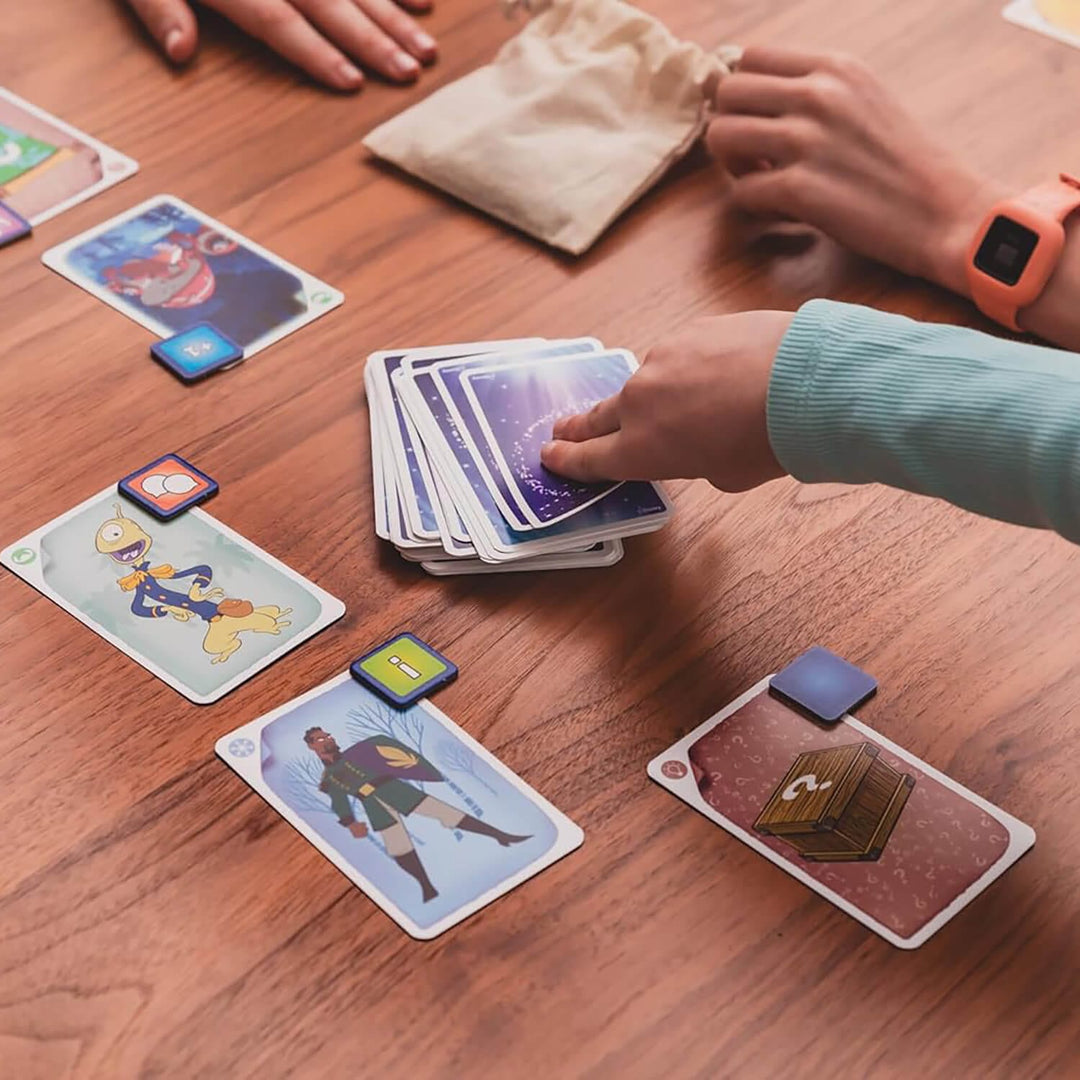 Card game in progress on a wooden table with colorful cards and hands interacting.