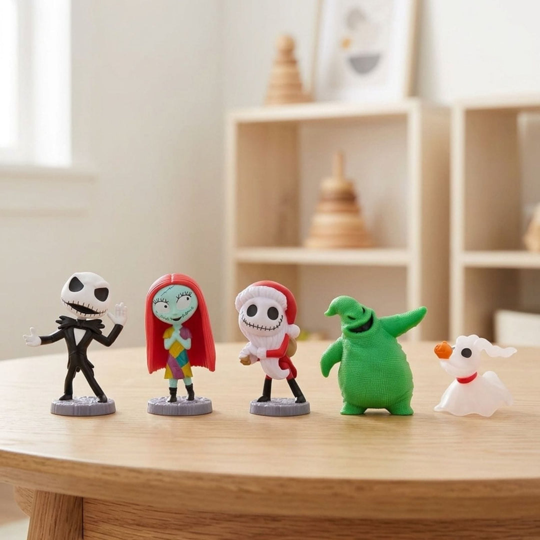 Five small character figurines from The Nightmare Before Christmas are lined up on a light wood table in a softly blurred indoor room. The figures include Jack Skellington, Sally, Zero, Oogie Bookie & Sandy Claws.