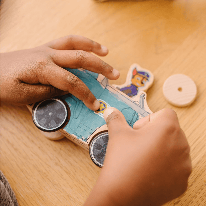 young boy adding shiny foil stickers to wooden block