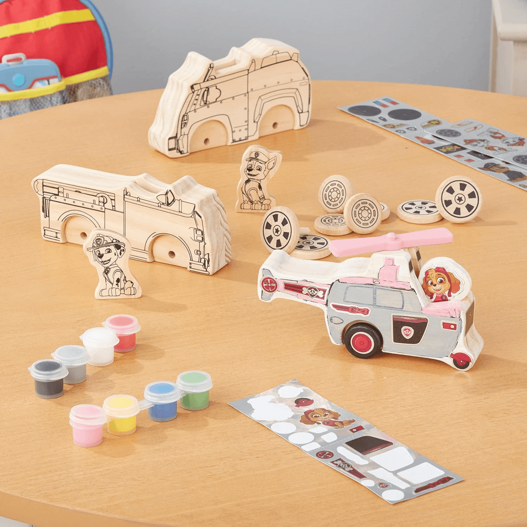 craft set contents laid out on wooden table top includes paint tubs, foil sticker sheets and wooden blocks and parts