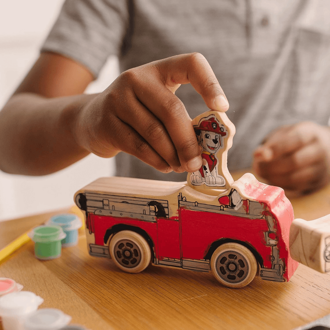 young boy adds paw patrol dog into painted fire engine