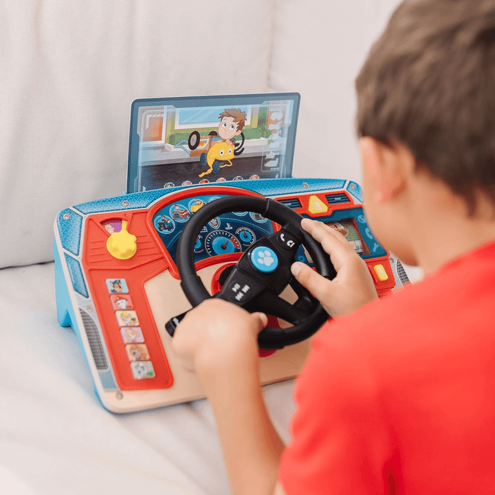 young boy turns the steering wheel on the paw patrol car dashboard