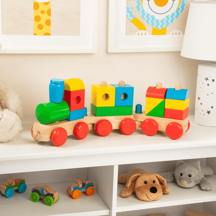wooden shape sorter train on white shelves in kids room with soft toys and lamp styled beside it