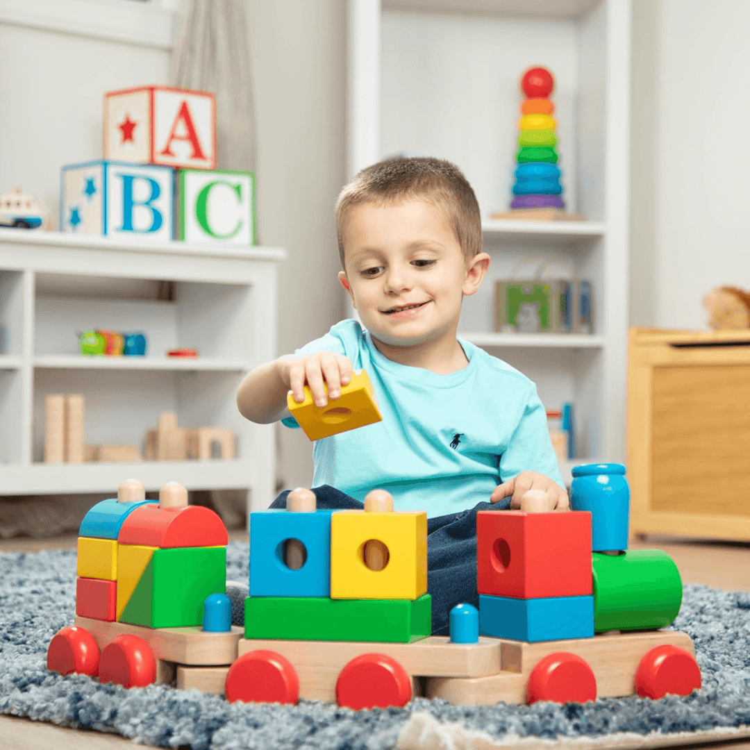little boy adds yellow block to train set in bedroom