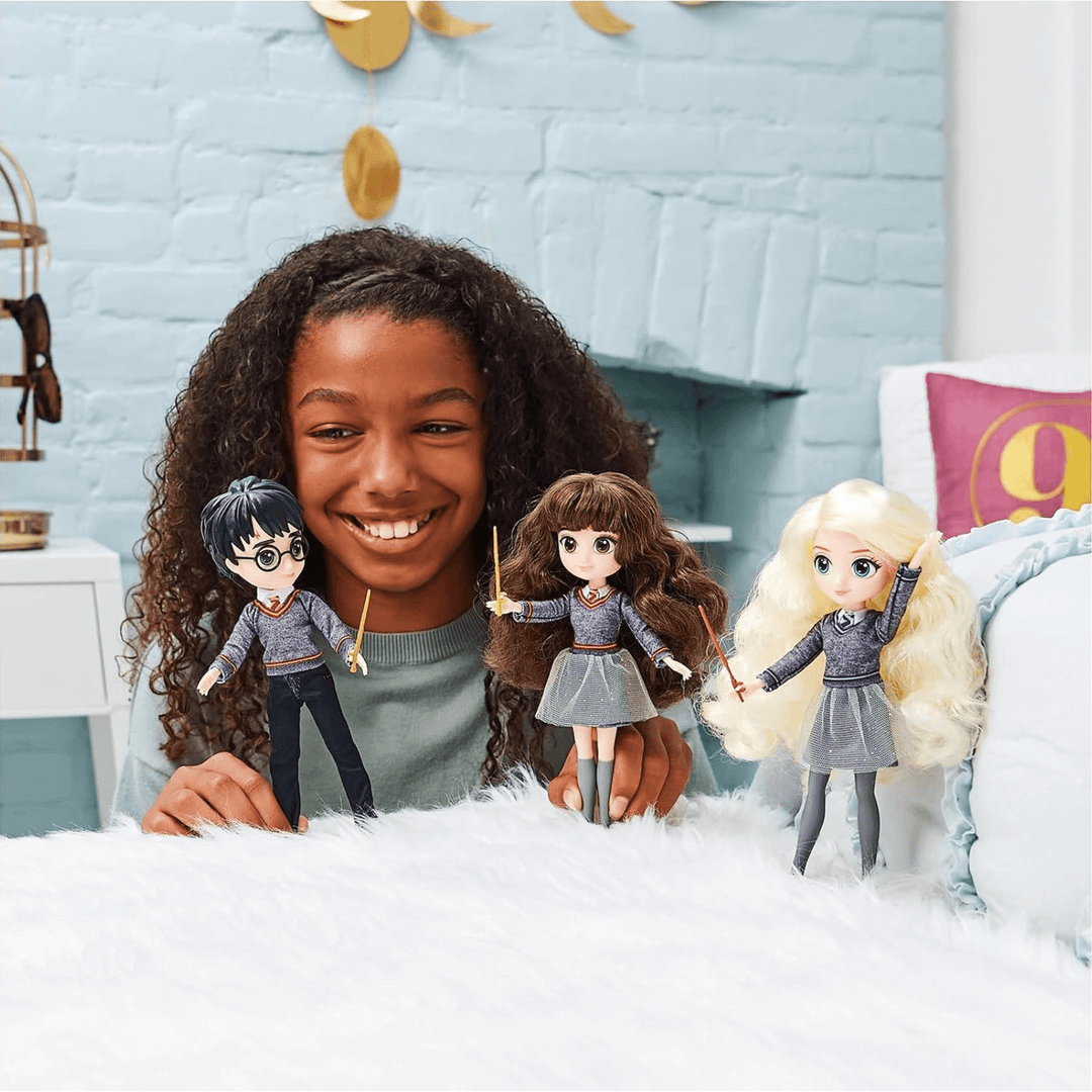 young girl smiles and plays with harry and hermione figures on bed in harry potter themed bedroom