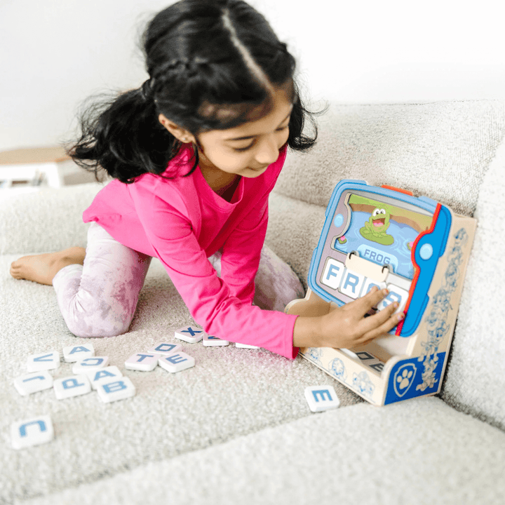 little girl uses letters to spell the words on the screen display 'frog'