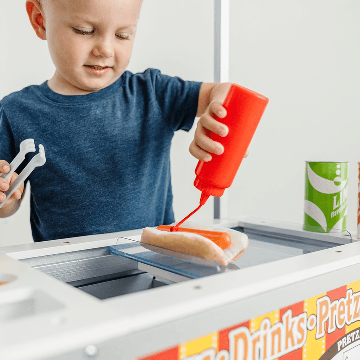little boy squeezes ketchup bottle and red string comes out to mimic ketchup going onto a burger