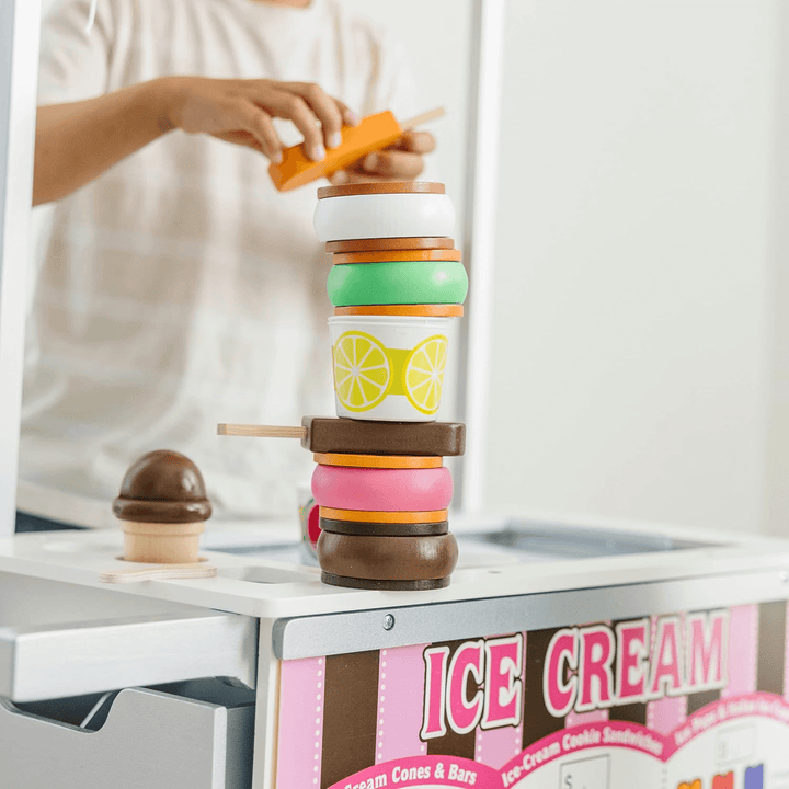 a pile of wooden pretend ice cream sandwiches a pops on top of ice cream cart