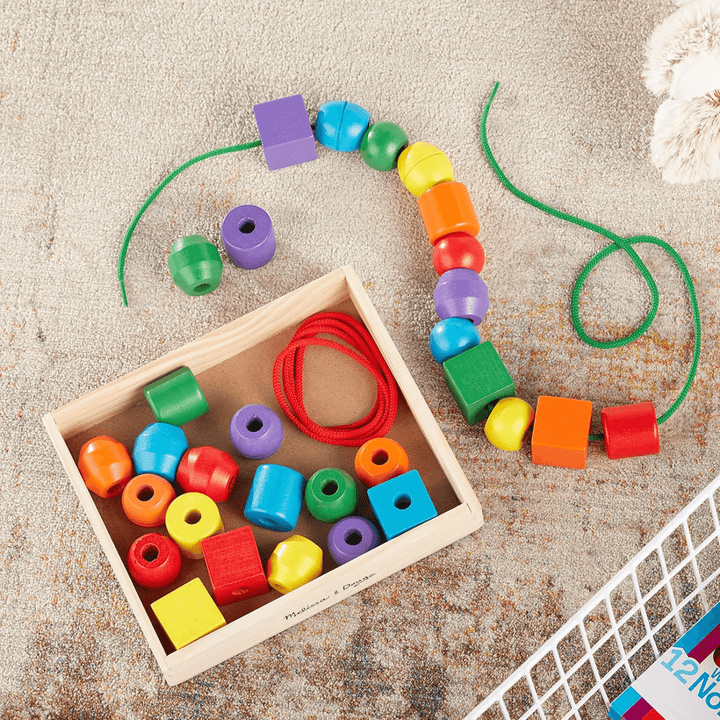 wooden bead set with storage box and laced beads on nautral colour carpet at home