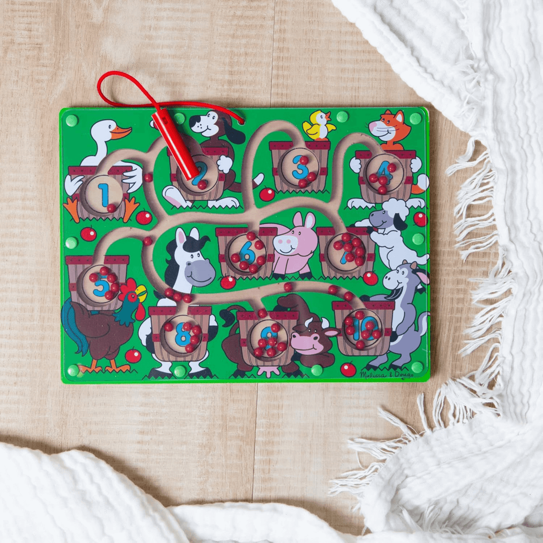 green farm animal puzzle maze on wooden floor in bedroom with blanket to the side