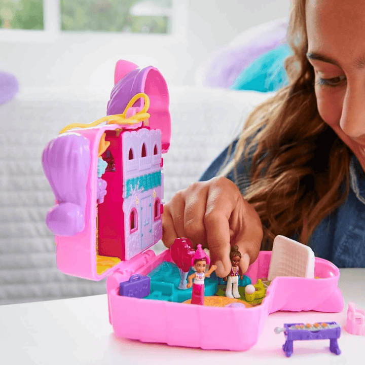 young girl plays with 2 polly pocket dolls inside the pinata party playset in her bedroom