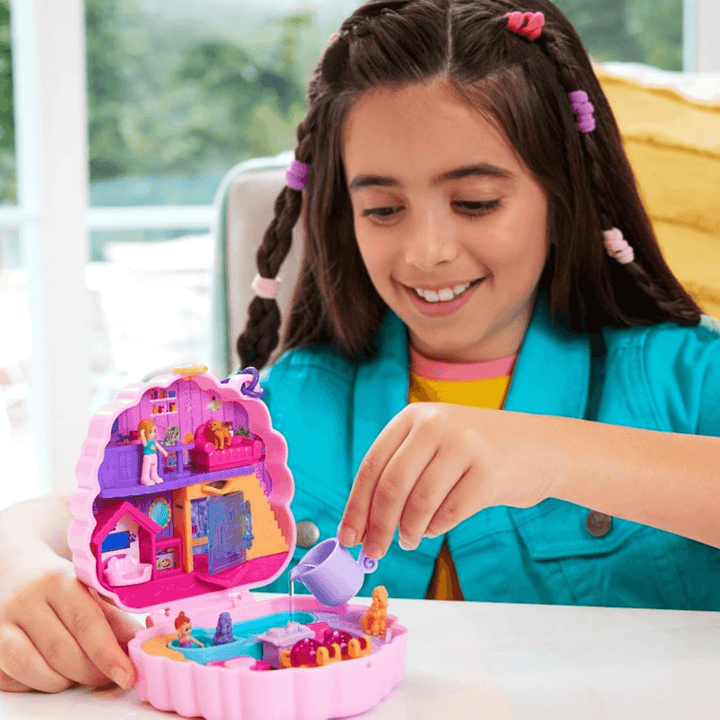 little girl fills bathtub for dogs with water using the purple coloured watering jug, smiling in her bedroom