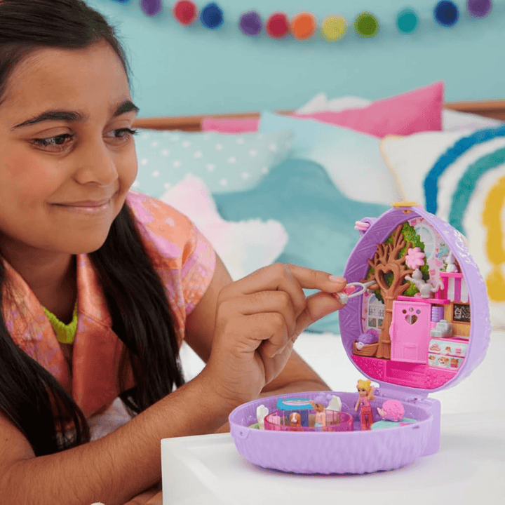 young girl attaches swinging bird cage to tree in hedgehog coffee shop compact, smiles as she plays in her bedroom