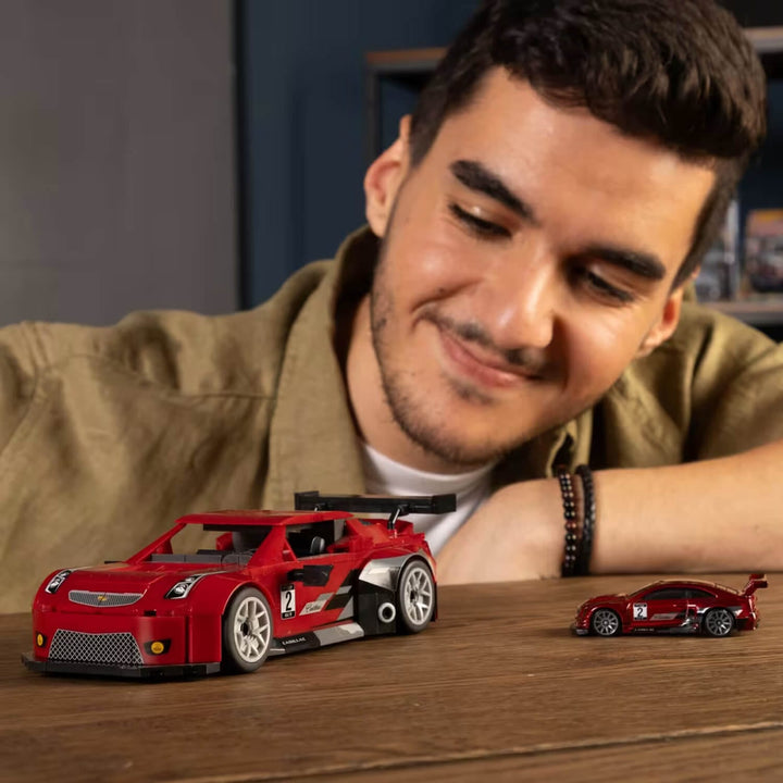 Person admiring a red cadillac collector car with die-cast model on table
