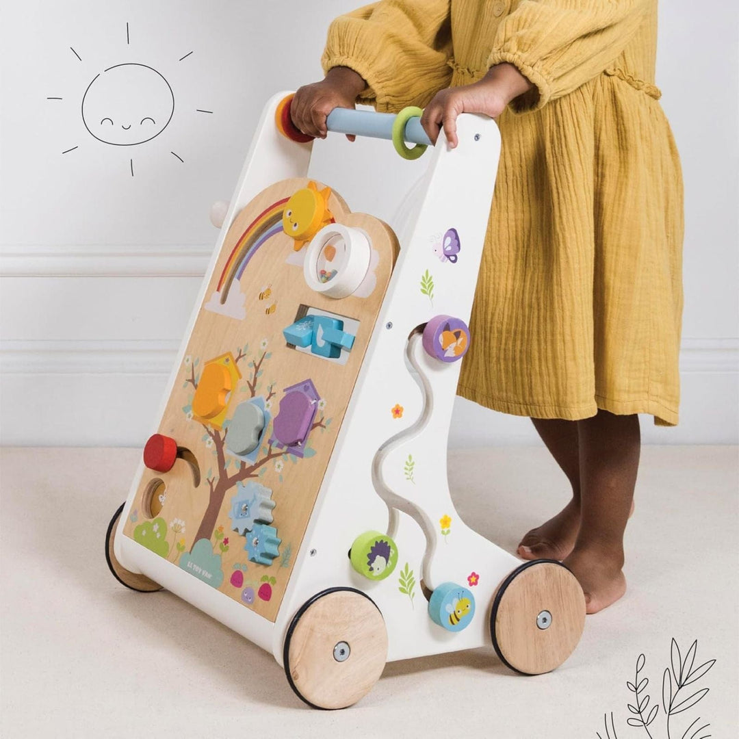little girl holds baby walker in bedroom