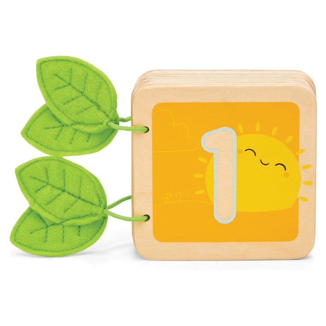 Wooden block with number 1 and sun design, bound by green felt leaves on a white background