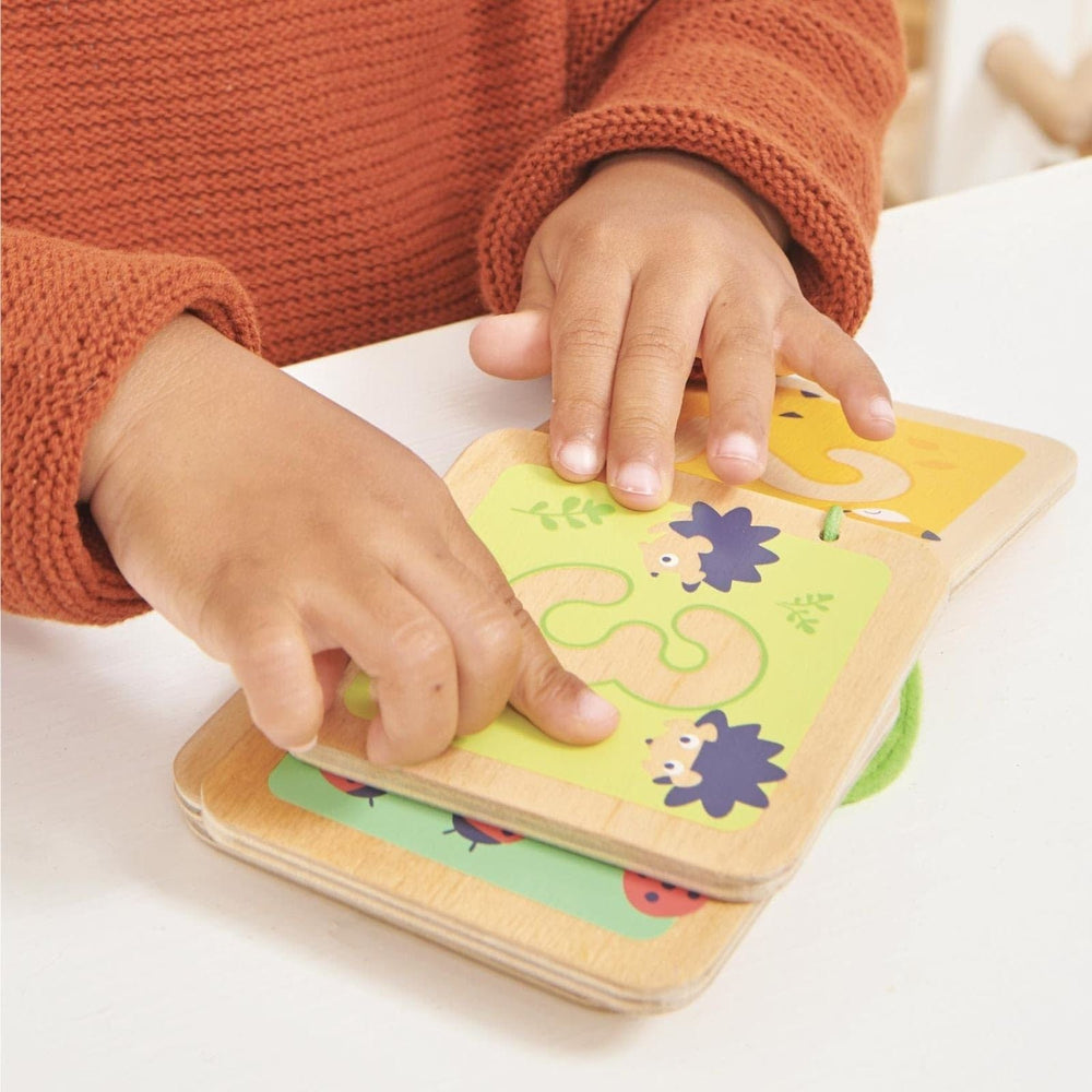 Child's hands interacting with a colorful wooden number book on a white surface