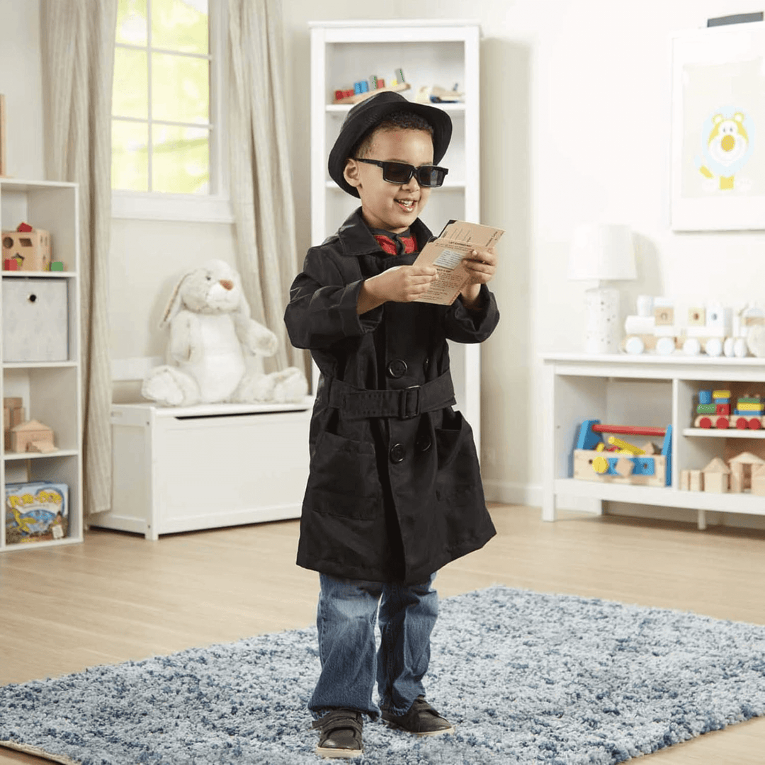 young boy in bedroom wearing spy costume with hat, jacket and holding secret files booklet