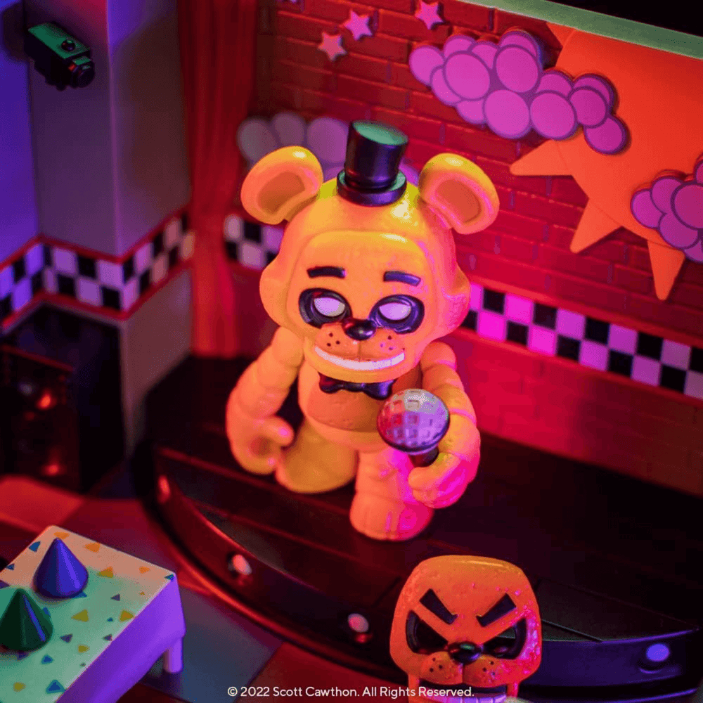 funko snaps goldren freddy in playset base holding microphone accessory with interchangeable face on floor beside table