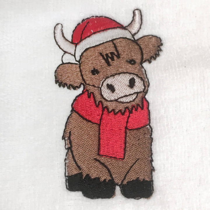 Embroidered patch of a Highland cow wearing a red scarf and Santa hat on a white background