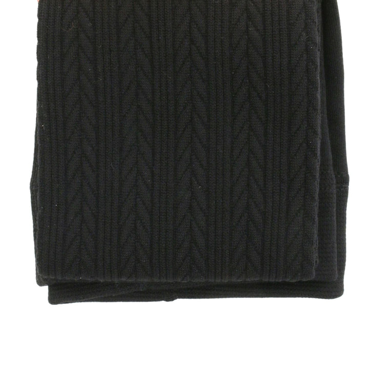 Folded black cable knit sweater on a white background