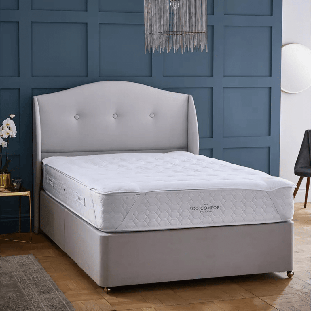 Gray bed with tufted headboard against a blue paneled wall
