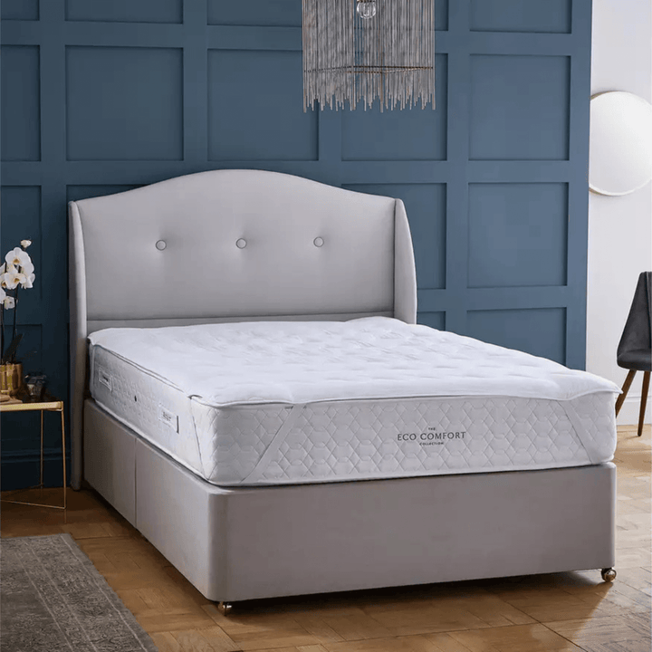 Gray bed with tufted headboard against a blue paneled wall