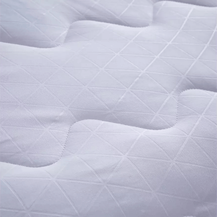 Close-up of a quilted white mattress pad with diamond pattern
