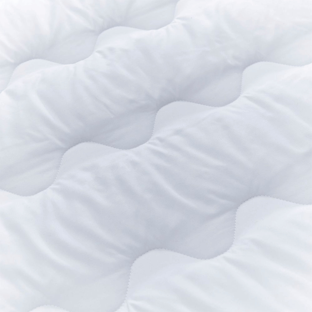 Close-up of a textured white surface on mattress topper with wavy patterns