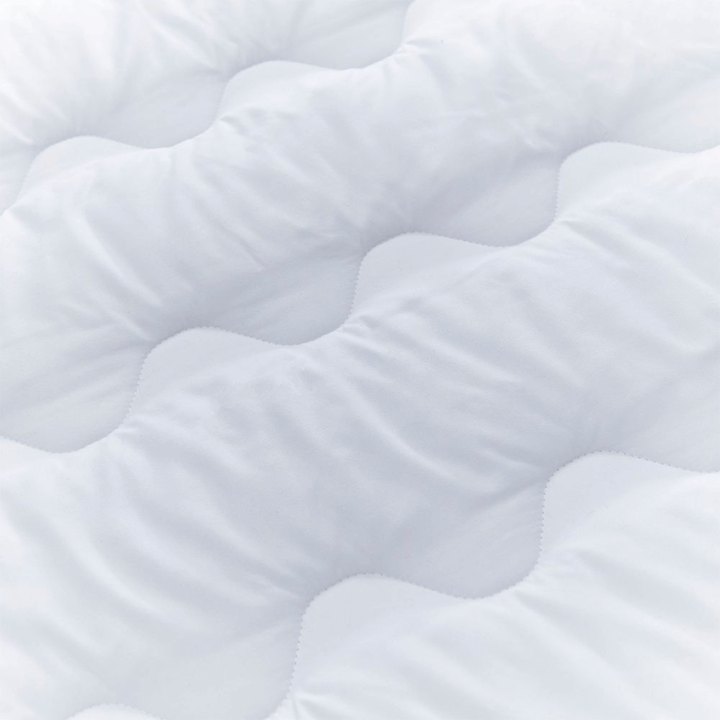 Close-up of a textured white surface on mattress topper with wavy patterns