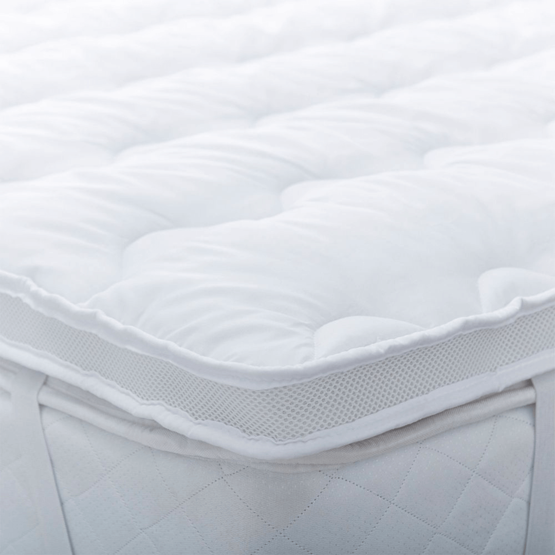 Close-up of a white quilted mattress cover on a bed with air mesh sides