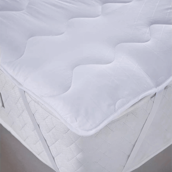 White quilted mattress topper on a bed