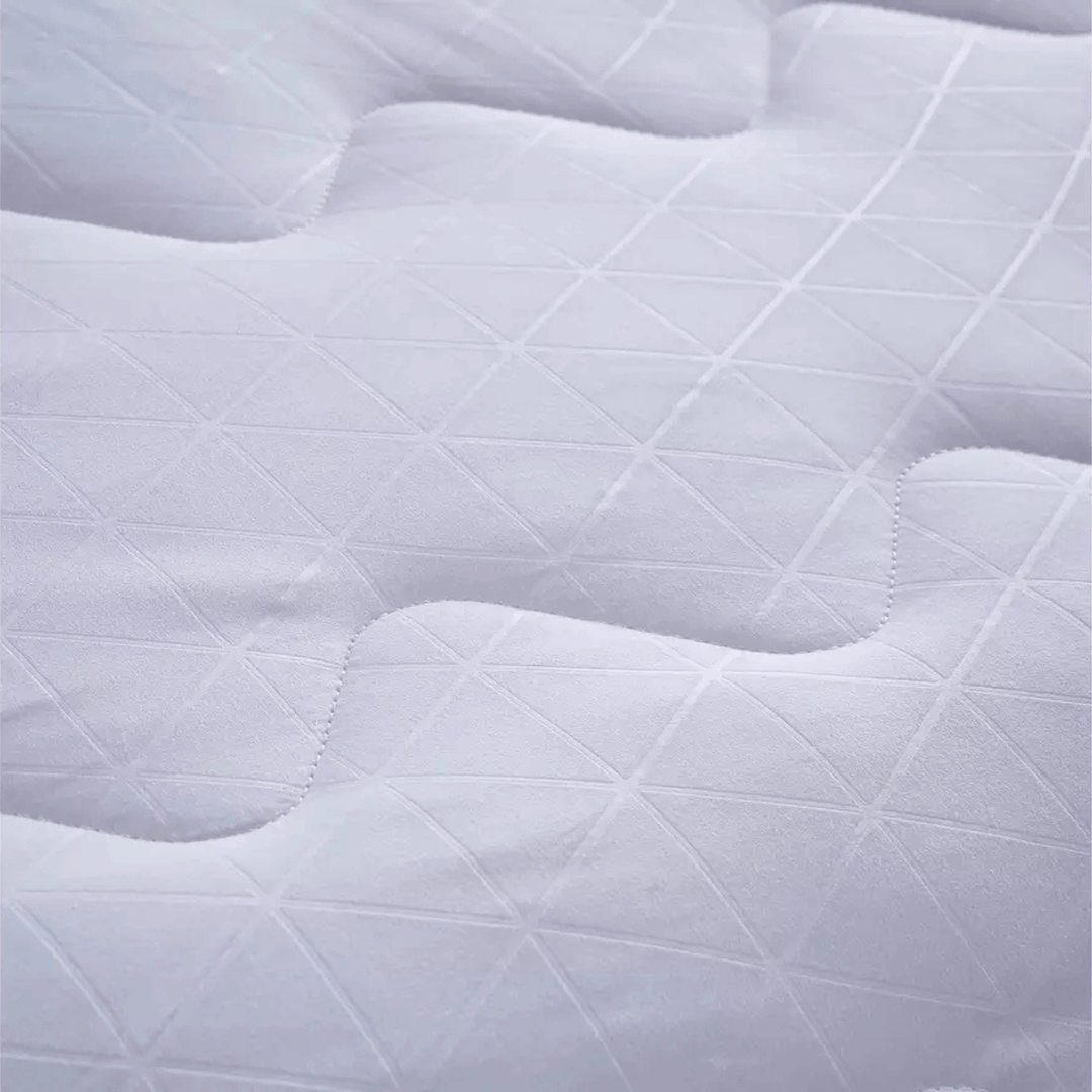 Close-up of a quilted white mattress pad with diamond pattern