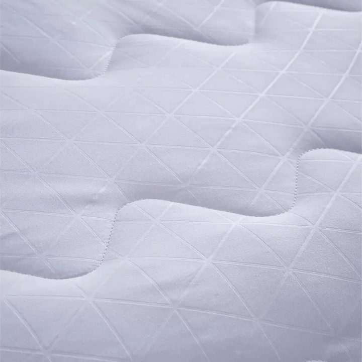 Close-up of a quilted white mattress pad with diamond pattern